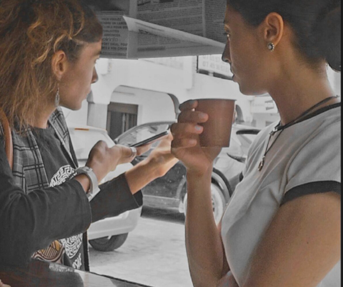 Omara et Inès Ré face à face, en discussion autour d'un carnet et d'une tasse.