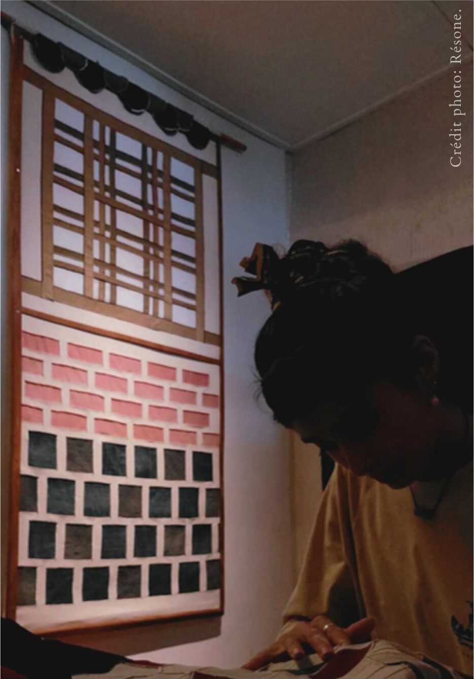 HANOKA installé sur un mur de l'atelier, une silhouette passe devant.