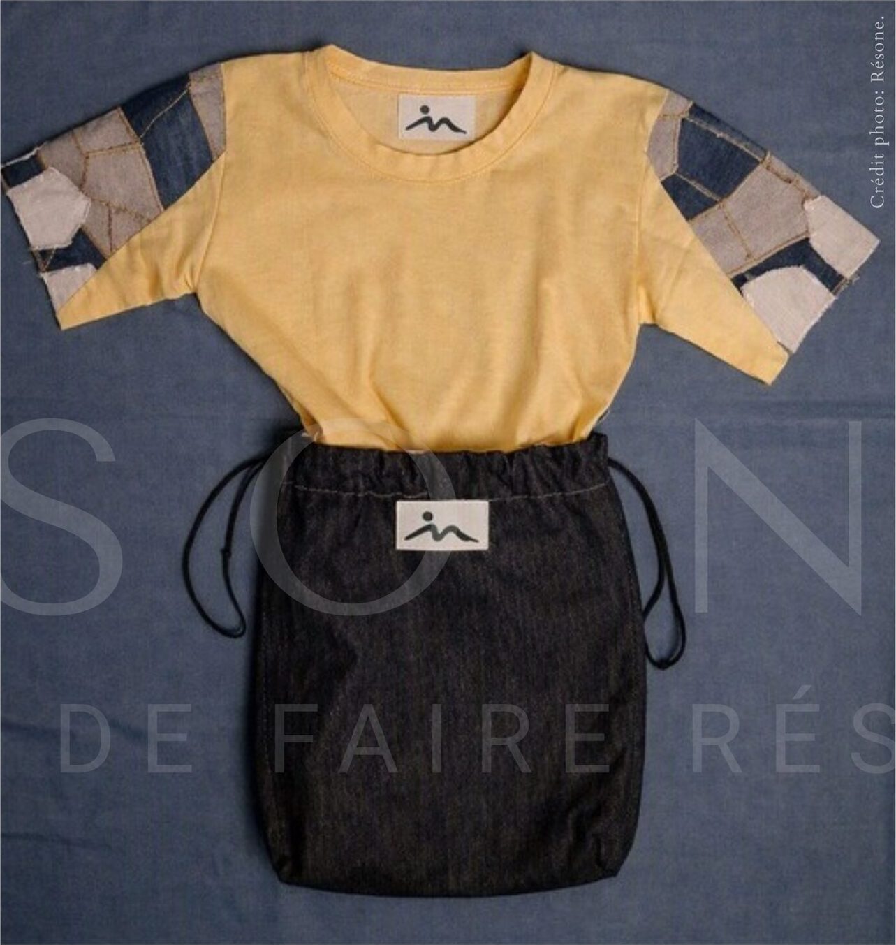 Haut jaune et jupe en denim noir portant le grain de beauté brodé.
