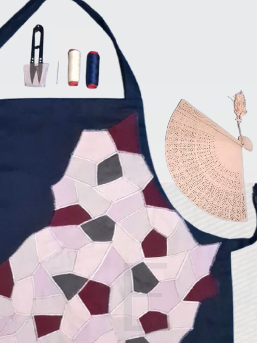 Tablier d'artisan en denim à patchwork rose et bordeaux, présenté avec un éventail.