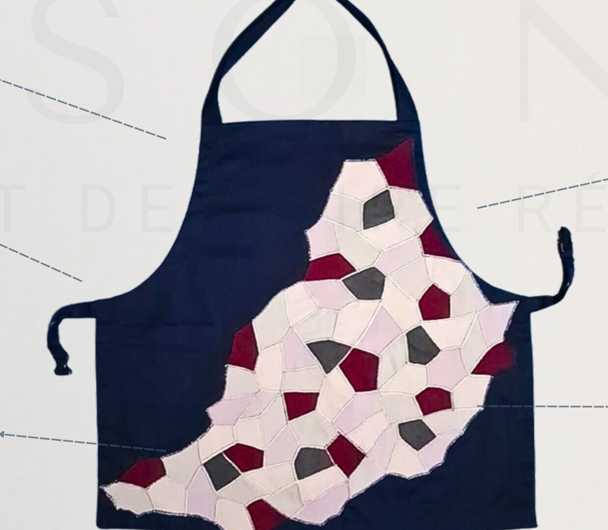 Tablier d'artisan en polycoton bleu marine, orné d'un patchwork géométrique.